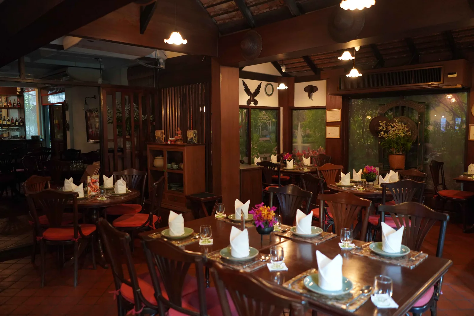 Warm timber dining room with set tables and Thai artwork at Baan Khanitha Sukhumvit 23