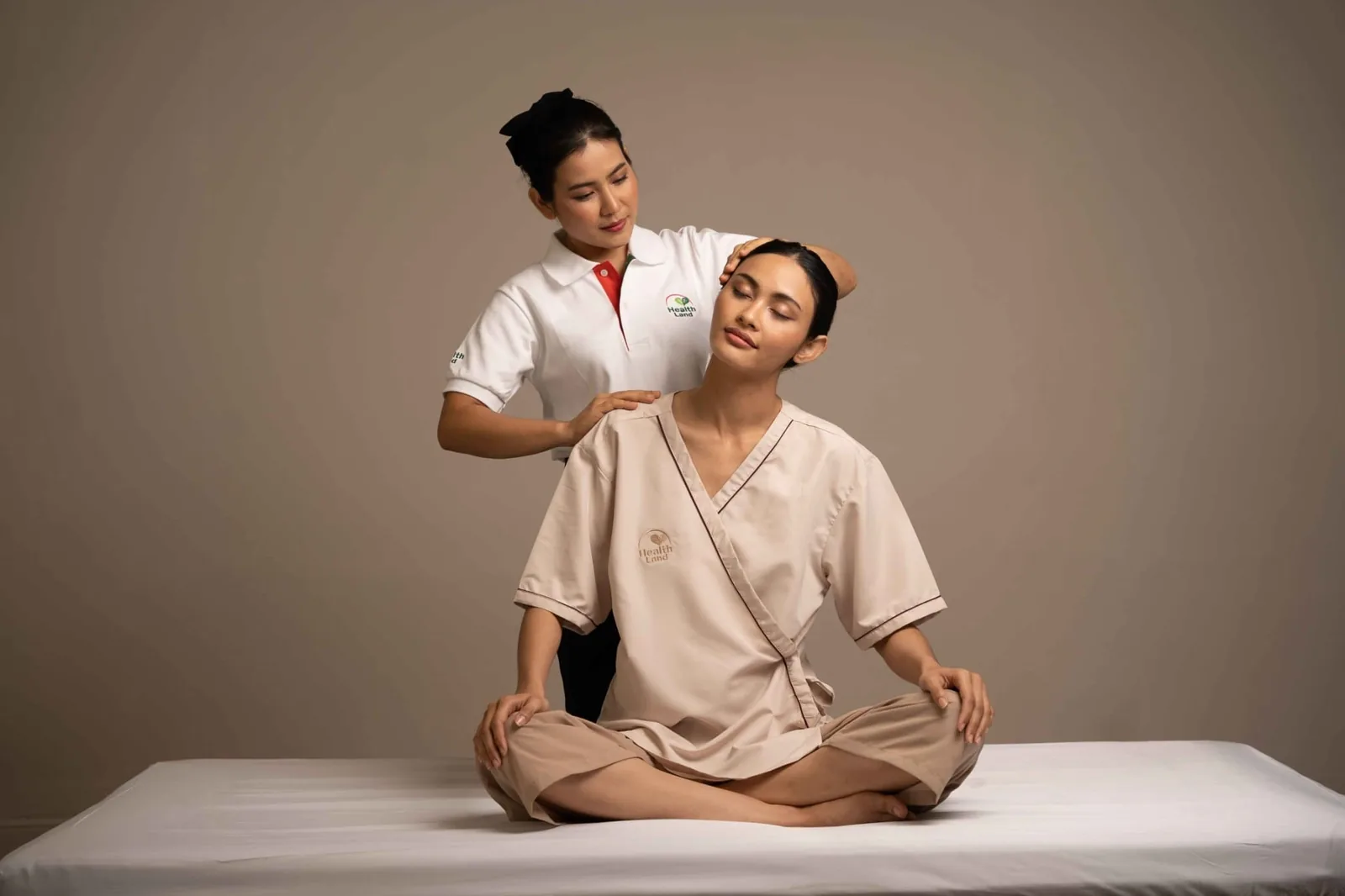 Health Land therapist applying a seated head and neck technique during traditional Thai massage